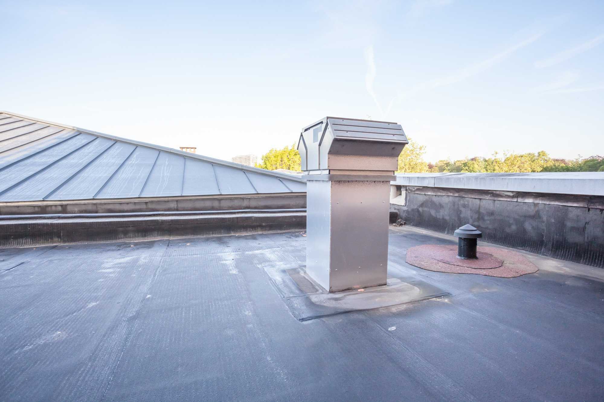 A metal chimney installed by commercial roofers on the roof of a building in Alhambra.