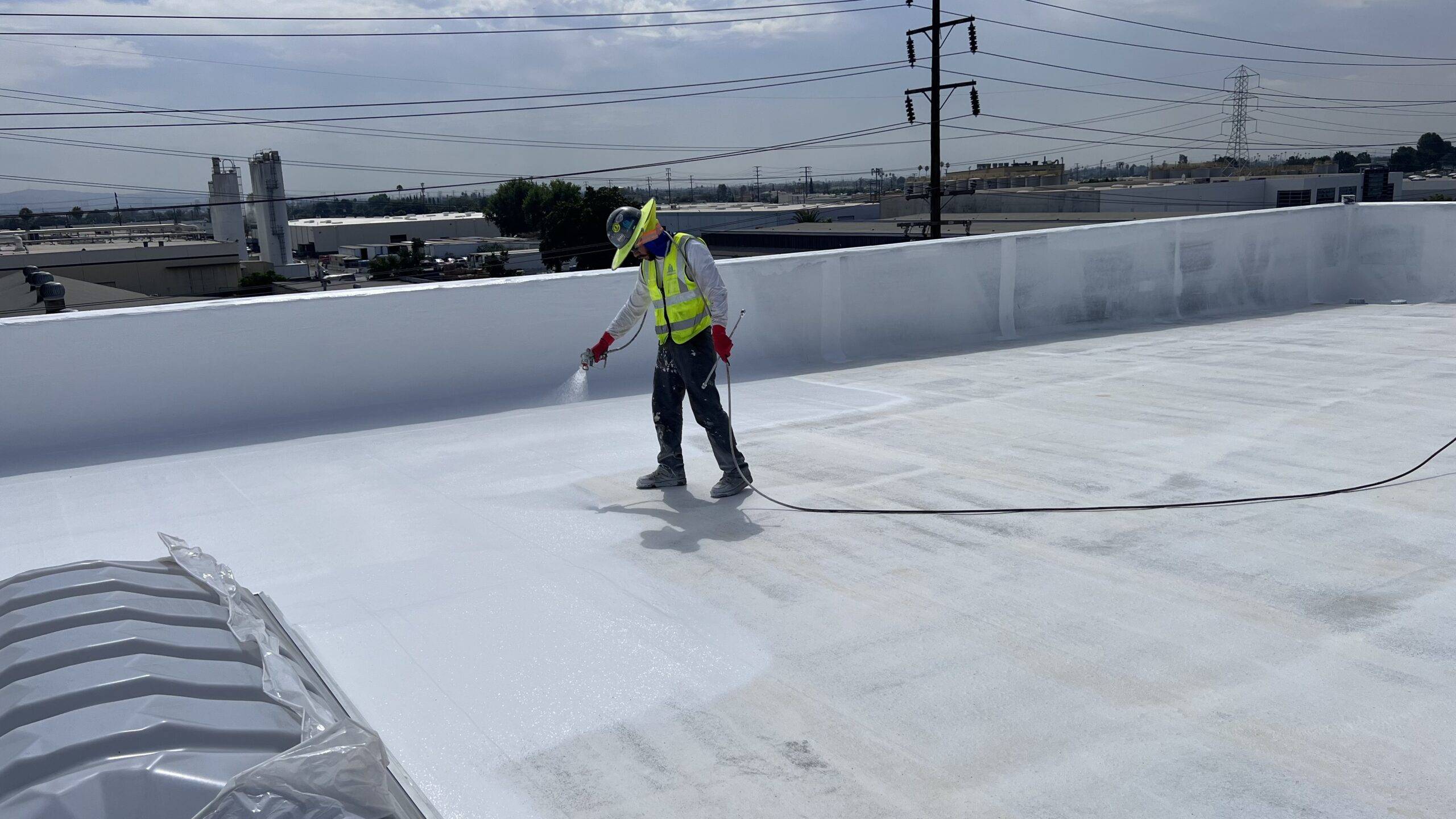 A man spraying a white roof with a hose.