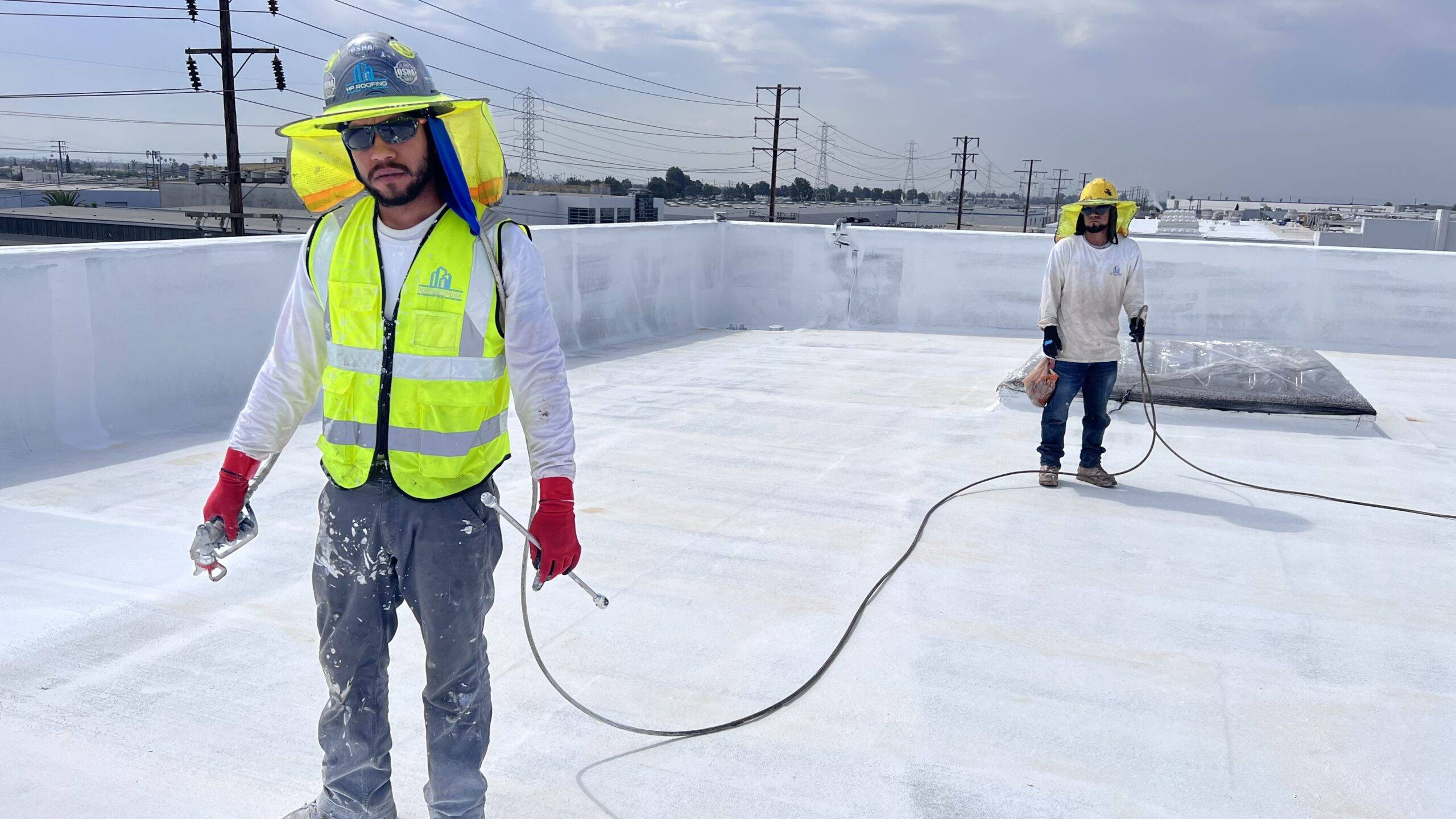 Two men working on a white roof.