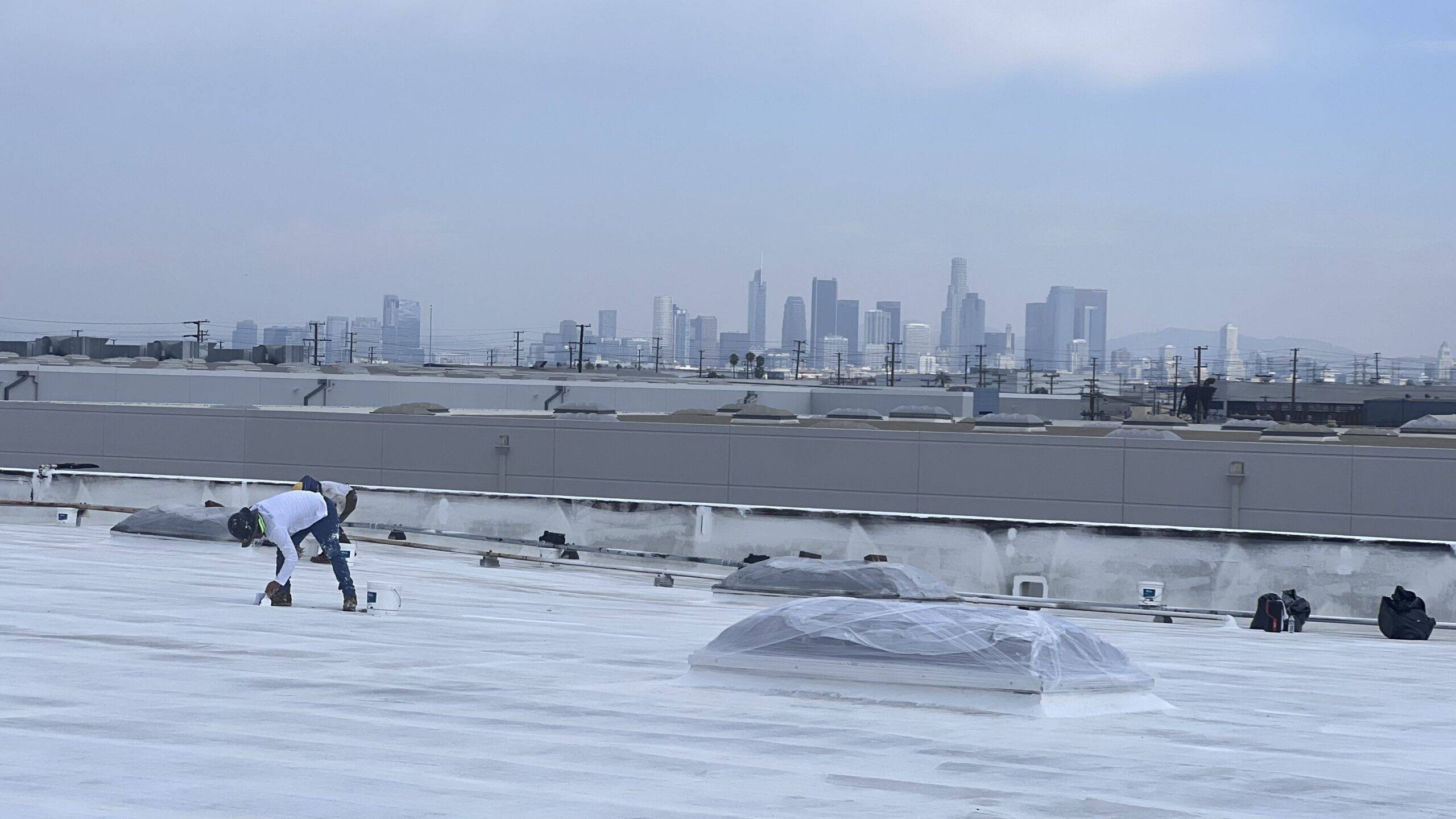A man is working on a roof with a city in the background.